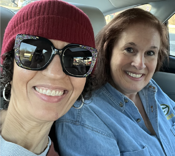 Geneva Perry and Tammy Gandolfo sitting side by side in a car, sharing a happy moment outside the office